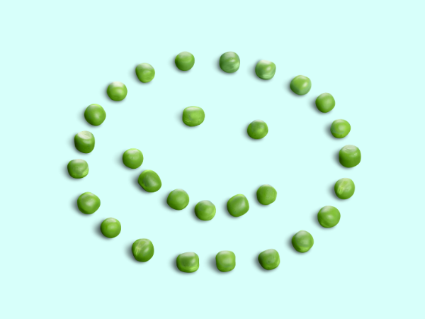A smiley face made out of peas, like this one on a light teal background, is another way to get kids to eat their veggies.